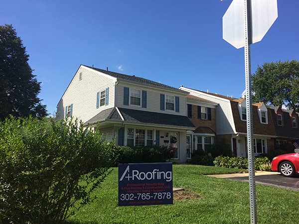 a sign in front of a house with a new roof
